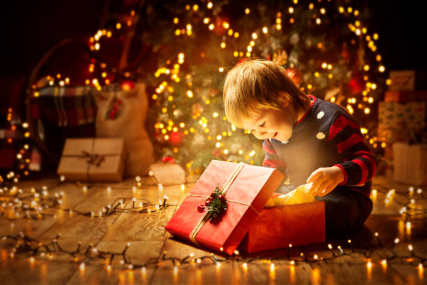 Child opening gift in front of tree